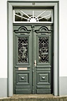 the front door to an old building with wrought iron work on it's doors