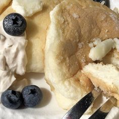 some blueberries and pancakes are on a plate with butter, syrup and ice cream