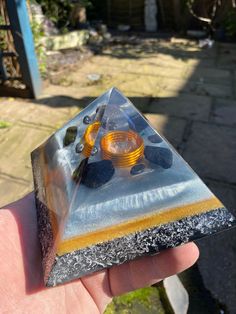 a hand holding a piece of glass with some yellow and black items in it's center