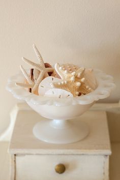 a white bowl filled with sea shells on top of a table