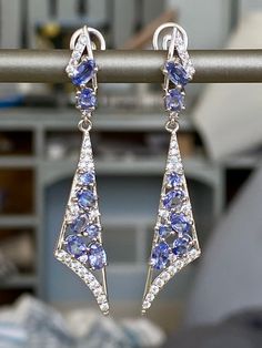 This is a fashion forward stylish earrings. The metal on this ring is 14K White gold plated sterling silver. The blue stones are beautiful oval cut 100% natural untreated Cornflower Blue Tanzanite from Tanzania. The accent stones are cubic zirconia (cz). Thai silver jewelries are well known for their craftsmanship and high silver content which keeps them from tarnishing through regular wear and tear. These types of rings are timeless in style and can be enjoyed & cherished by every generation. T Sapphire Tanzanite Jewelry With Matching Earrings, Silver Tanzanite Drop Earrings, Blue Tanzanite Teardrop Earrings, Fine Jewelry Tanzanite Earrings In Sapphire Color, Fine Jewelry Sapphire Tanzanite Earrings, Blue Tanzanite Drop Earrings, Sapphire Tanzanite Earrings Fine Jewelry, Fine Jewelry Tanzanite Drop Earrings, Tanzanite Teardrop Jewelry With Matching Earrings