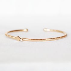 "Elegant, modern and sparkly! Hand forged out of 2mm 14k gold with a 2mm white diamond and a handmade petal. The cuff is not hollow, it is solid gold all the way through. The diamond and petal are set off-center on the cuff. I balled the ends with my torch. Simple and elegant, the perfect skinny cuff for every day wear! Diamond - 2mm I1 White, conflict-free Gold - 2mm 14k Cuff is 5.5\"L and has an opening of approximately 1\". It fits medium to small wrists and is slightly adjustable. If you wou Gold Minimalist Bangle With Single Cut Diamonds, Minimalist Diamond Cuff Bracelet As A Gift, Minimalist Gold Bangle With Single Cut Diamonds, Minimalist Diamond Cuff Bracelet For Anniversary, Gold Cuff Bracelet With Single Diamond As Gift, Minimalist Bangle With Single Cut Diamonds For Gift, Elegant Cuff Bracelet With Single Diamond Gift, Minimalist Bangle With Single Cut Diamonds, Gold Bangle With Single Diamond For Gift