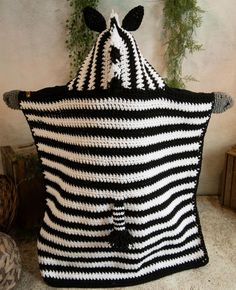 a large black and white striped bag sitting on top of a table next to a potted plant