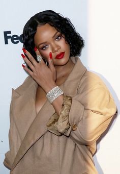 a woman holding her hand up to her face while posing for the camera with red nail polish