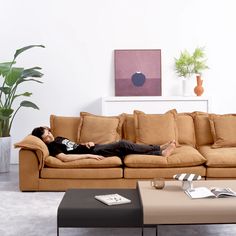 a woman laying on top of a couch in a living room next to a coffee table