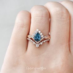 a woman's hand with a blue and white diamond ring on top of it