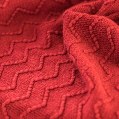 closeup of red knitted fabric with wavy lines and zigzag pattern