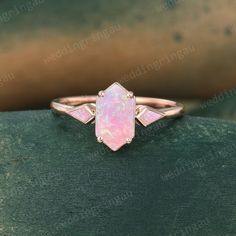 a pink opalite ring sitting on top of a green surface