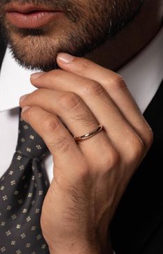 a close up of a person wearing a suit and tie with a ring on his finger