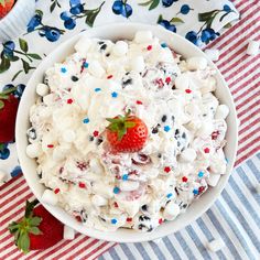 a bowl filled with white chocolate and strawberries on top of a striped table cloth