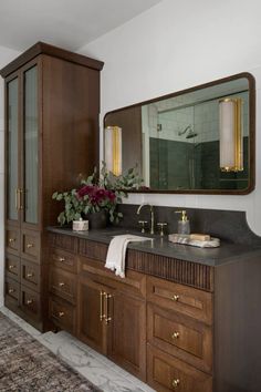 a bathroom with wooden cabinets, marble counter tops and large mirror above the vanity area