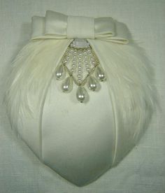 This unique deco bridal hat is strongly influenced by 1930s styling and takes elements from vintage bridal pieces. It was created with lightly padded off-white satin over a lightweight straw base, with a hand stitched soft feather trim and a glass bead and silver wire decoration. The piece is completed with a tailored satin bow. The reverse is finished with traditional millinery petersham and a comb bound with satin ribbon. The hat is 12.5cm at the widest point and 15cm long. The comb will sit s Vintage Wedding Hat With Pinched Crown, Vintage Wedding Costume Hat With Pinched Crown, White Gatsby Style Fascinator For Evening, Vintage White Fascinator For Evening, Vintage White Evening Fascinator, Vintage Pinched Crown Headpiece For Weddings, Vintage Cream Fascinator For Wedding, Vintage Wedding Fascinator Headband, Elegant Cream Fascinator For Vintage Events