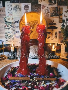 two red candles are in the middle of a bowl