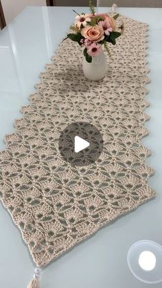 a crocheted table runner with flowers in a vase on the top and a video screen showing how to use it