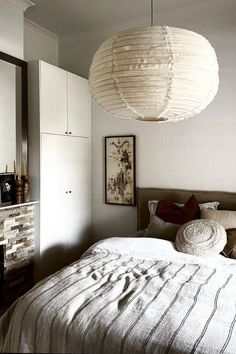 a bedroom with a bed, mirror and hanging light fixture in the middle of it