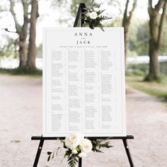 the seating chart for an outdoor wedding ceremony is displayed on a easel with white flowers and greenery