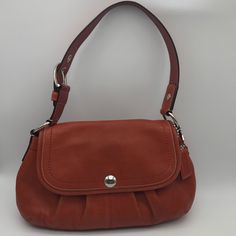 Coach Soho Shoulder Bag. This Bag Is A Beautiful Burnt Orange With Silver Hardware. Unique Color. Front Button Closure, One Open Exterior Pocket, One Large Open Back Interior Pocket And Two Smaller Open Pockets And One Smaller Zipper Pocket. Plenty Of Space For All Your Essential Items. *Tiny Ink Spot On Back Right Corner Some Rubbing Of The Material On Back And Front. Condition: Good L: 14.5” X H: 7” X W: 4” Coach Hangtag Strap Drop: 8.5” Wide Strap Adjustable Two Hole Strap Tags: Coach; Vintag Designer Shoulder Bag With Snap Closure For Everyday Use, Elegant Leather Hobo Bag With Snap Closure, Classic Hobo Shoulder Bag With Snap Closure, Leather Handles Flap Satchel, Coach Flap Shoulder Bag For Everyday Use, Coach Leather Shoulder Bag With Magnetic Closure, Elegant Hobo Shoulder Bag With Snap Closure, Elegant Hobo Bag With Snap Closure, Coach Shoulder Bag With Magnetic Closure For Everyday