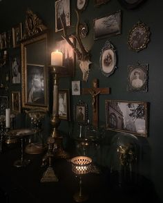 a wall with pictures and candles on it in a room filled with other things,