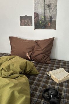 an unmade bed with two books and headphones on the floor next to it