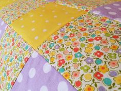 a close up of a colorful quilt with polka dots and flowers on the bottom half