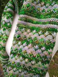 a close up of a person wearing a green and white knitted shawl with flowers on it