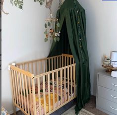 a baby's crib in the corner of a room with a green canopy over it