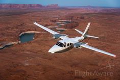 a small plane flying over some water in the desert