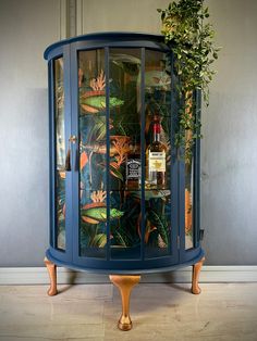 a blue cabinet with plants and liquor bottles in it