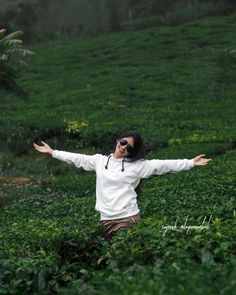 a woman standing in the middle of a field with her arms spread out and eyes closed