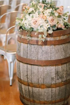 a wooden barrel with flowers and greenery on it at a wedding ceremony or reception