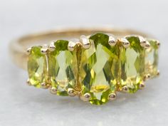 This stunning cocktail band is truly breathtaking and perfectly polished. The proportions are lovely, providing a safe and secure setting for the bright, brilliant grass-green peridots set throughout the center! This ring sits low to the hand, making it a great piece for the evening or with a fancy dress! Metal: 14K Yellow GoldGem: 5 Peridot totaling 2.83 CaratsGem Measurements: 5.0 x 9.9 mm, OvalRing Size: 10 Gold Peridot Ring, Peridot Jewelry, Hand Making, Gold Cocktail, August Birthstone, Oval Ring, Birthstone Gifts, Oval Rings, Peridot Ring