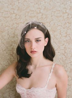 a woman wearing a birdcage veil over her head