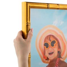 a person holding up a painting of a girl with sun glasses and a straw hat