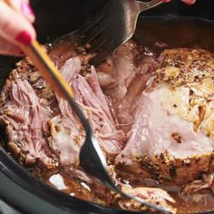 someone is cutting meat in the slow cooker with a knife and fork on it