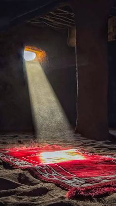 a light shines through a hole in the sand with a red rug on it