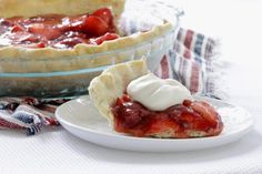 a slice of strawberry pie on a plate next to a bowl of strawberries and whipped cream