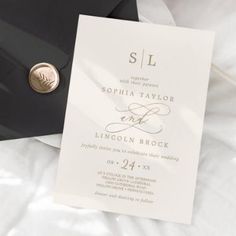 a wedding suite and tie laying on top of a white sheet with a gold button