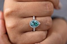 a woman's hand holding an engagement ring with a blue diamond in the center