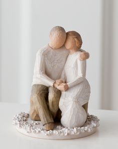 a figurine of two people hugging each other on top of a white table