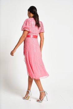 Bring a touch of joy to any special summer occasion with the strawberry pink Cleo. Designed in a faux wrap silhouette, this darling style features a dip hem, v neckline and sparkling silver embellishment. This knee length piece is cinched at the waist with a self tie satin bow. Glamorous V-neck Dress For Wedding Guest, Glamorous Embellished V-neck Midi Dress, Pink V-neck Midi Dress For Wedding Guest, Embellished Sequin Midi Dress For Spring, Spring V-neck Sequin Prom Dress, Spring Bridesmaid Midi Dress With Surplice Neckline, Summer Embellished Midi Sequin Dress, Feminine Pink Dress With Surplice Neckline, Summer V-neck Sequin Prom Dress