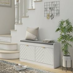 a living room with white furniture and a plant on the floor in front of stairs