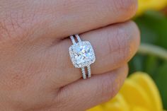 a woman's hand with a ring on it and a yellow flower in the background