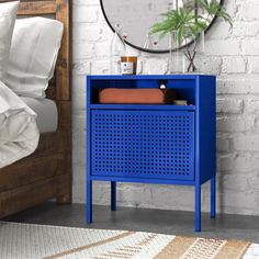 a blue cabinet sitting on top of a bed next to a night stand with pillows