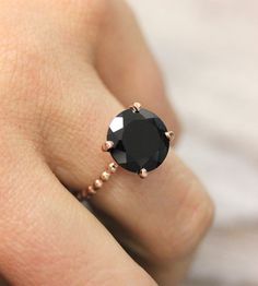 a woman's hand with a black diamond ring on top of her finger,