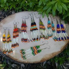 a group of beaded earrings sitting on top of a wooden slice