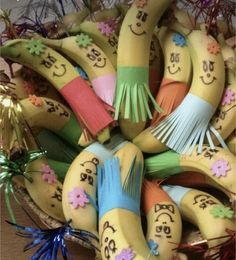 a bunch of fake bananas with faces and words painted on them, sitting in a basket