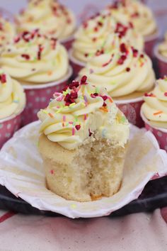 cupcakes with white frosting and sprinkles are on a plate