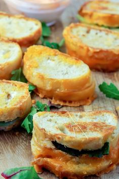 small sandwiches with cheese and spinach on a cutting board