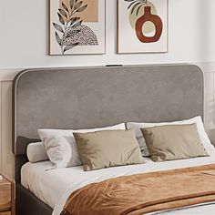 a bed with four pillows on top of it and two pictures above the headboard