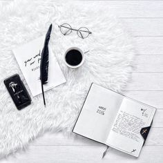 an open book, pen, eyeglasses and other items on a white rug